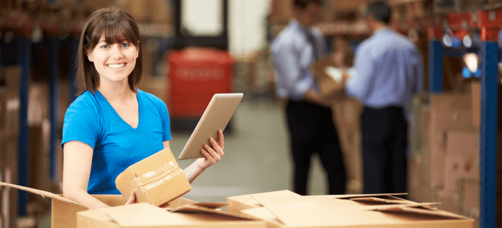 Warehouse operative using mobile device to sort cartons for shipping from China to Singapore, with managers in background
