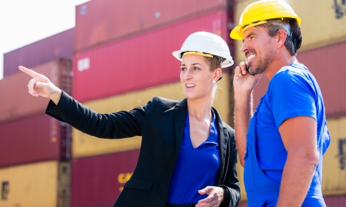 Two people discussing next to containers to find the right freight forwarder with Shipa Freight