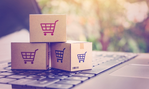 Three small cardboard boxed, featuring trollies, on the keyboard of a laptop