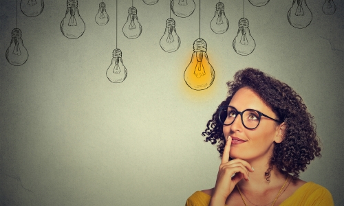 Woman thinking with drawing of a lit light bulb above her head as she finds ideas