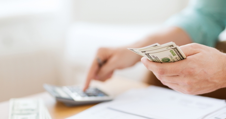 Closeup view of person holding money and using a calculator for customs hold daily fees